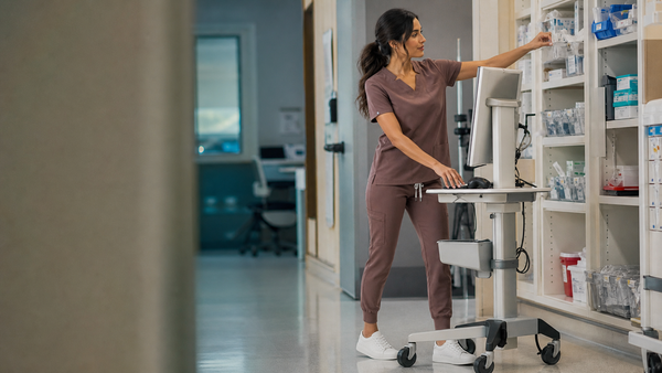 Healthcare worker adjusting an ergonomic workstation in mocha scrubs